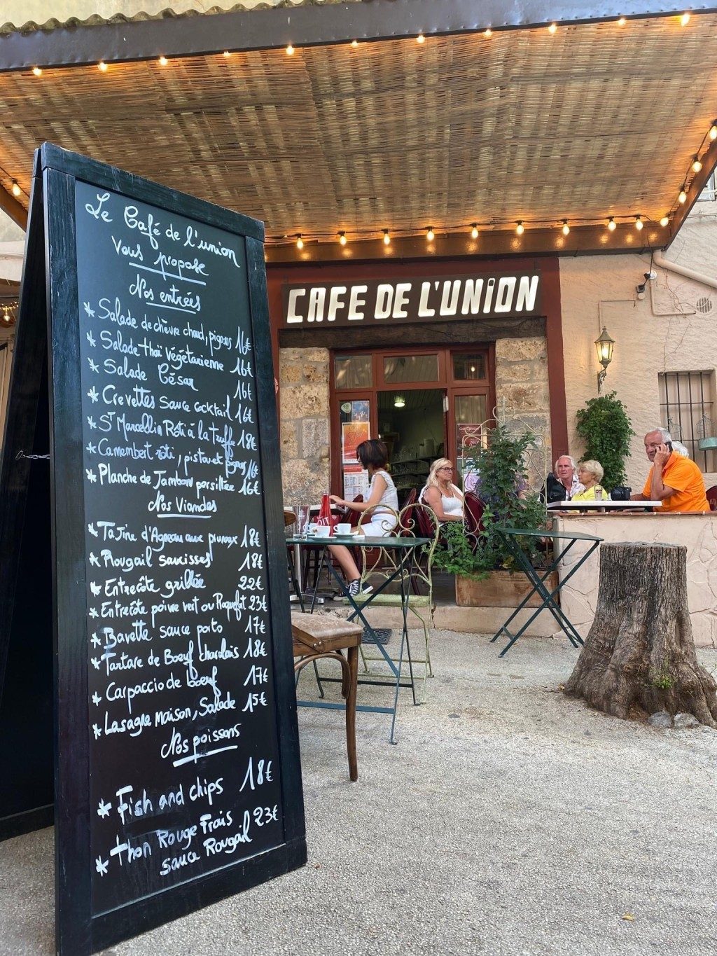 L'ardoise du jour devant le café, sous l'auvent éclairé